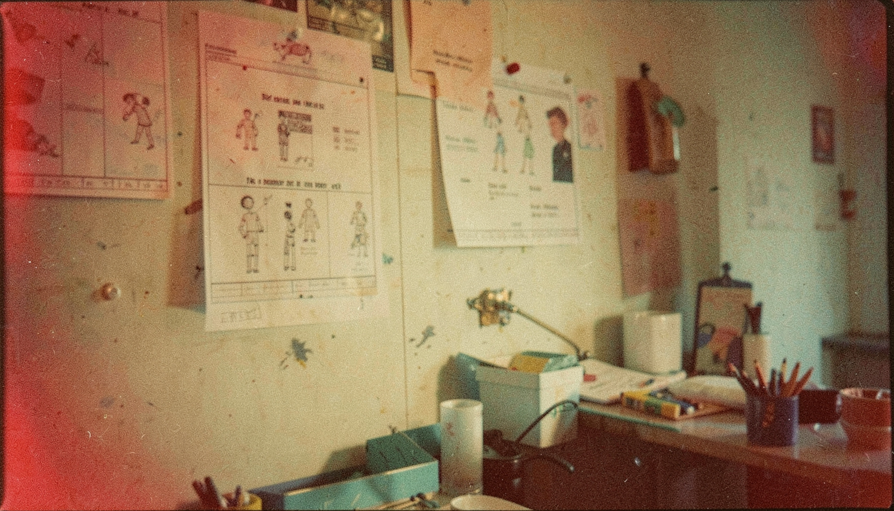 A softly lit analog film still of a creative workspace with storyboards pinned to a wall, warm amber and muted teal tones, visible film grain